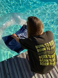 une fille avec un tshirt marron est assise près d'une piscine